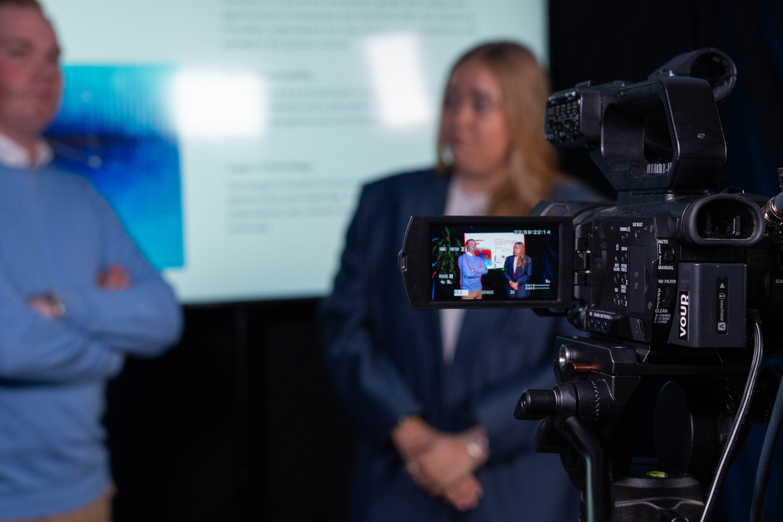 kaksi asiakasta kuvattavana kameran edessä, etualalla 4K-videokamara