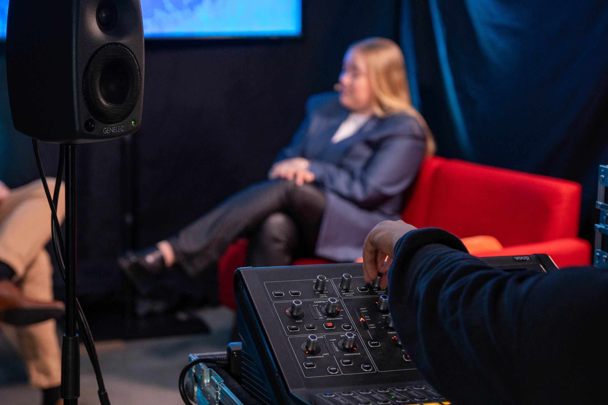 Miksaaja miksaamassa, kuvassa myös asiakas studion sohvalla sekä Genelec kaiutin